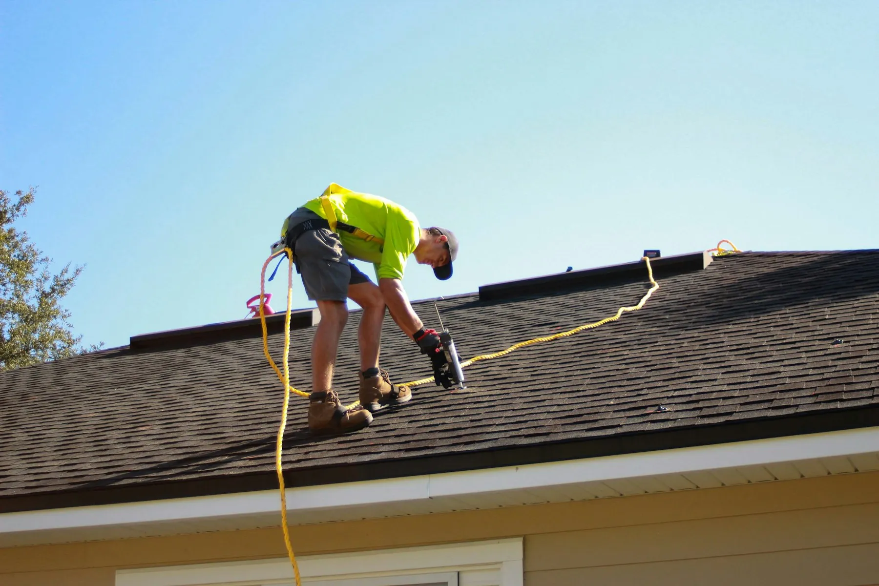 A roofer working on a roof with a power drill